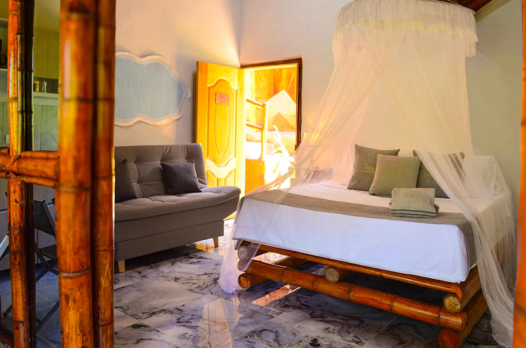 Habitación de Aire con cama de bambú, toldo blanco y sofá gris