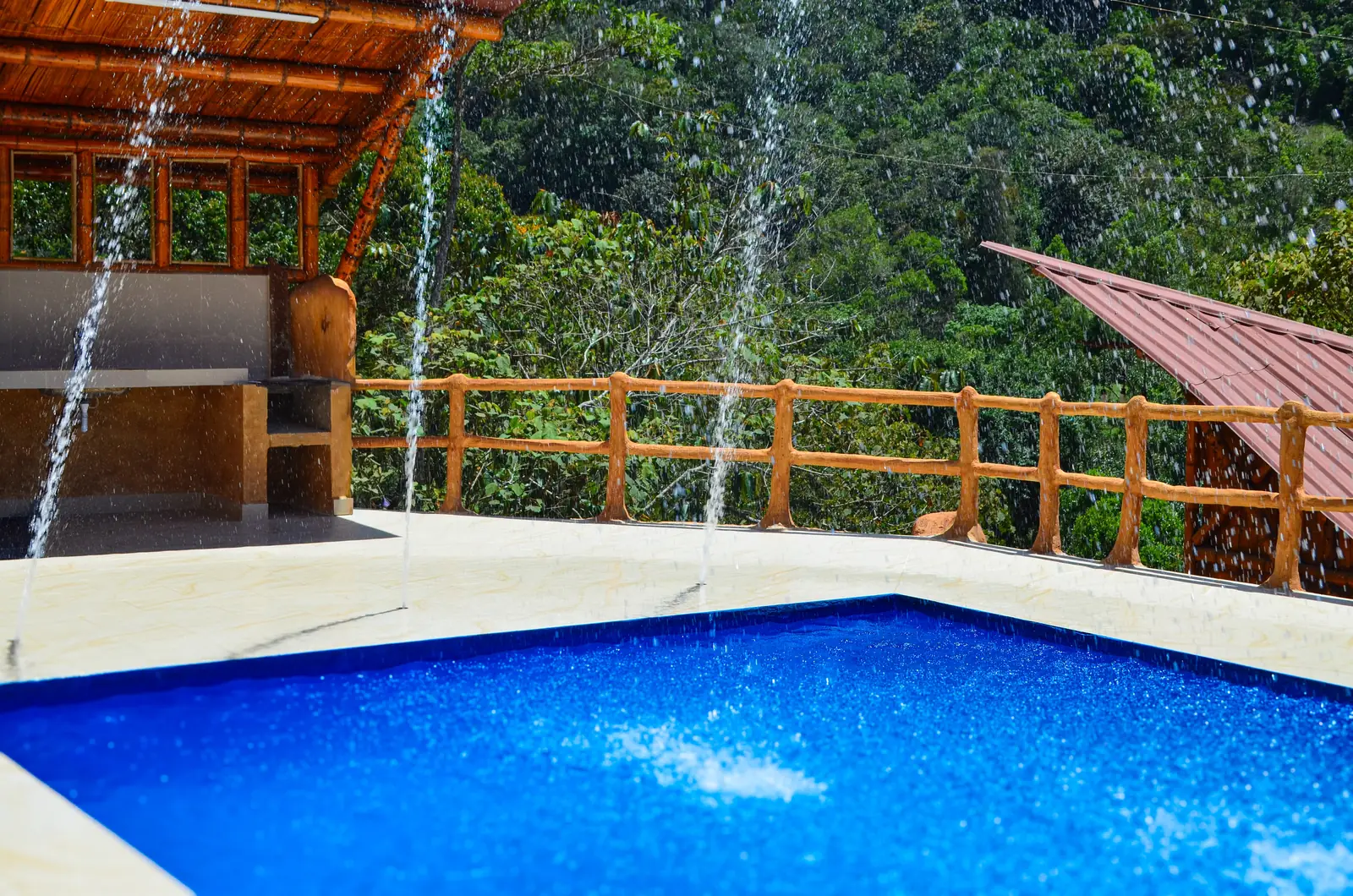 Piscina con chorros de agua y baranda de madera frente a la montaña
