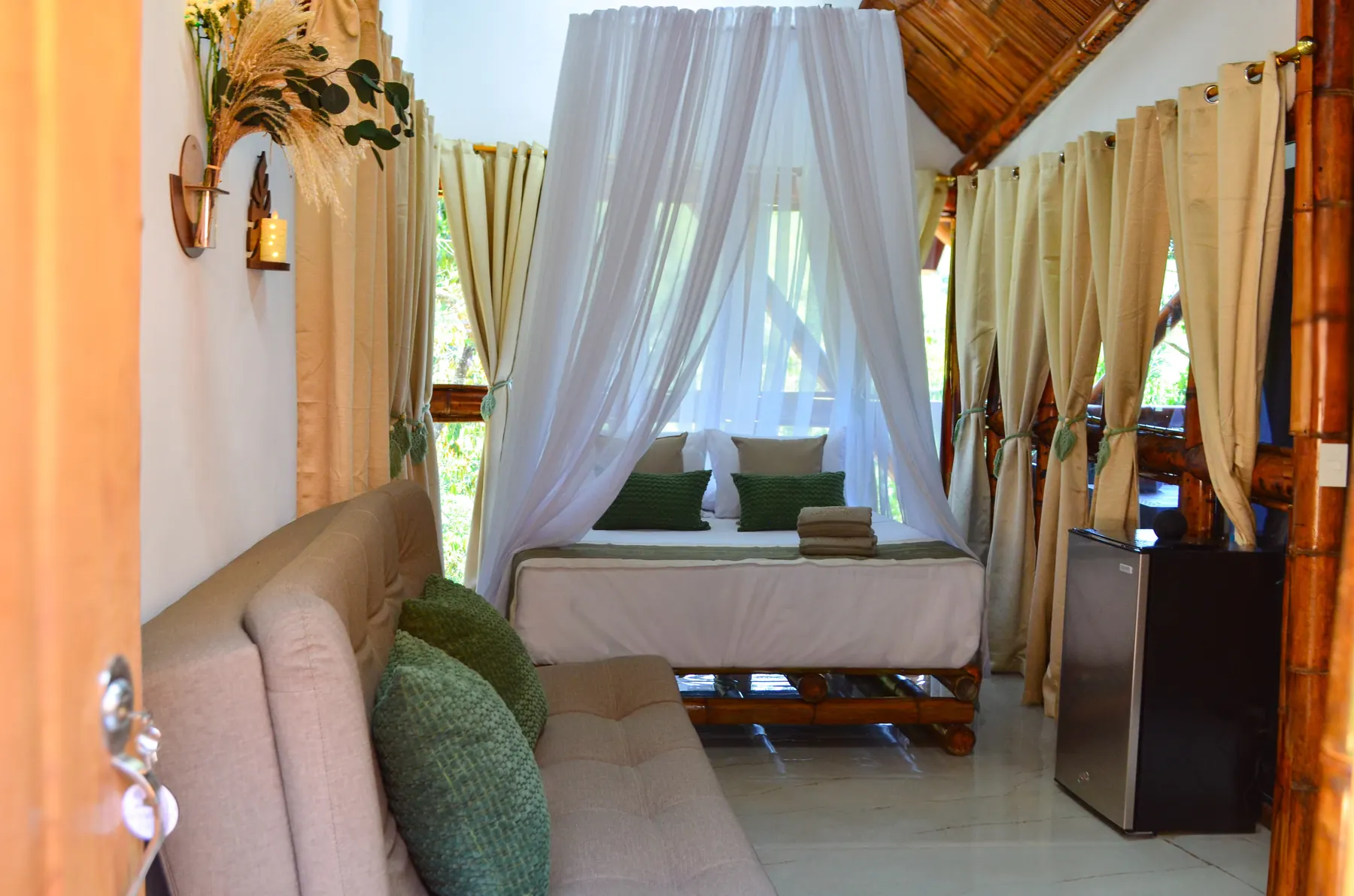 Habitación de Tierra con cama de bambú, toldo y cojines verdes